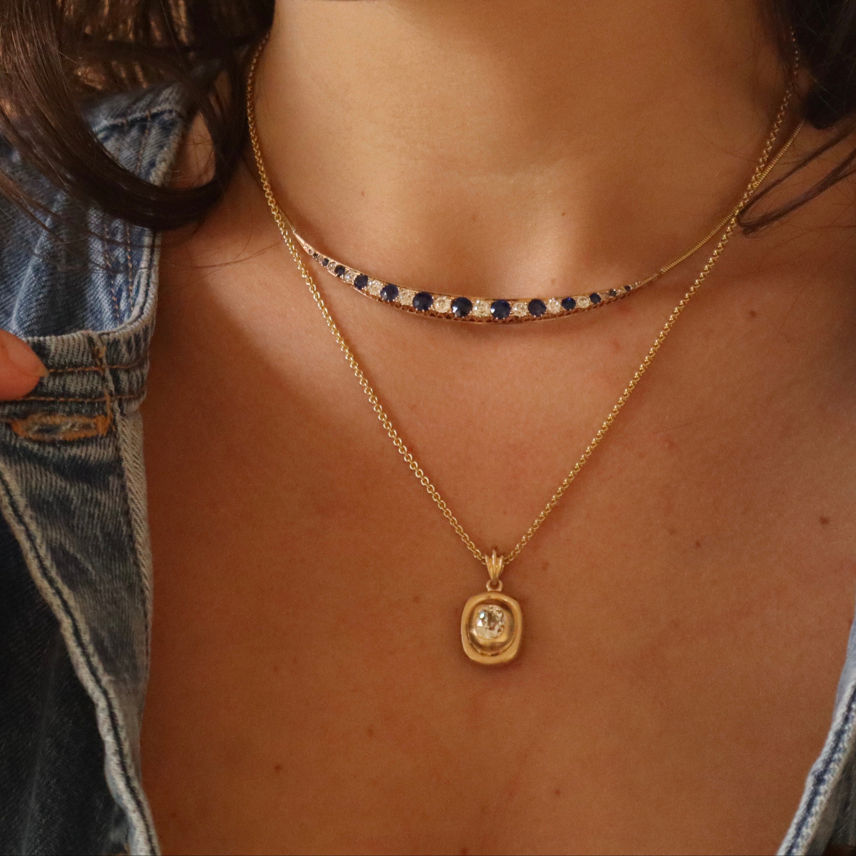 Close-up of a person wearing gold necklaces with diamonds and sapphires