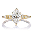 The Alix 1.03 is a gold ring with a large marquise-cut diamond at the center, accented by smaller round diamonds set into the tapered band on both sides.