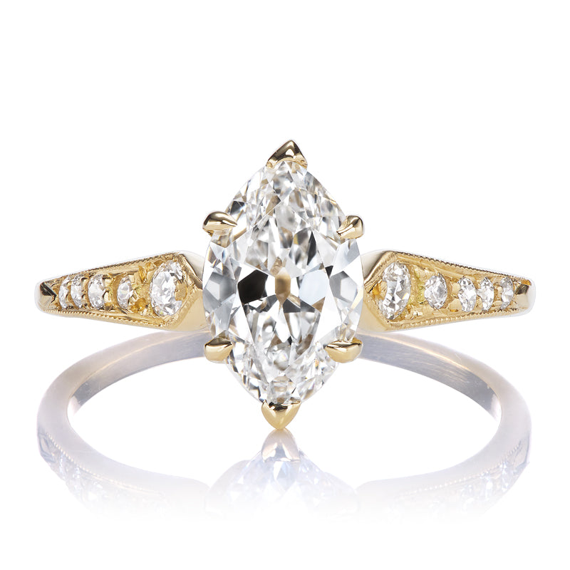 The Alix 1.03 is a gold ring with a large marquise-cut diamond at the center, accented by smaller round diamonds set into the tapered band on both sides.