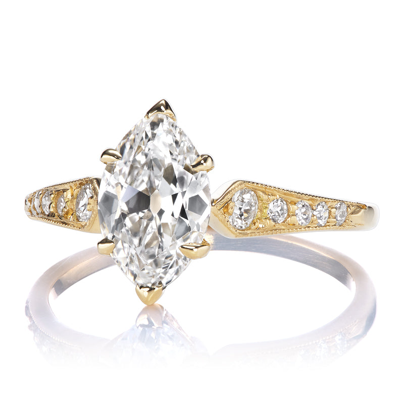 The Alix 1.03 is a gold ring with a large, oval-cut center diamond and smaller round diamonds set along its tapered band.