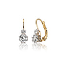 The Estelle 1.29 features gold drop earrings, each with a large round diamond accented by a smaller diamond above, set in prongs with lever-back clasps, displayed on a white background.