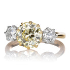 The PENDING Marielle 2.34 is a gold ring with a large round yellow diamond center, accented by two smaller round white diamonds on each side, all in prong settings.