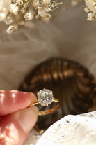 Diamond ring held by a hand with a blurred background